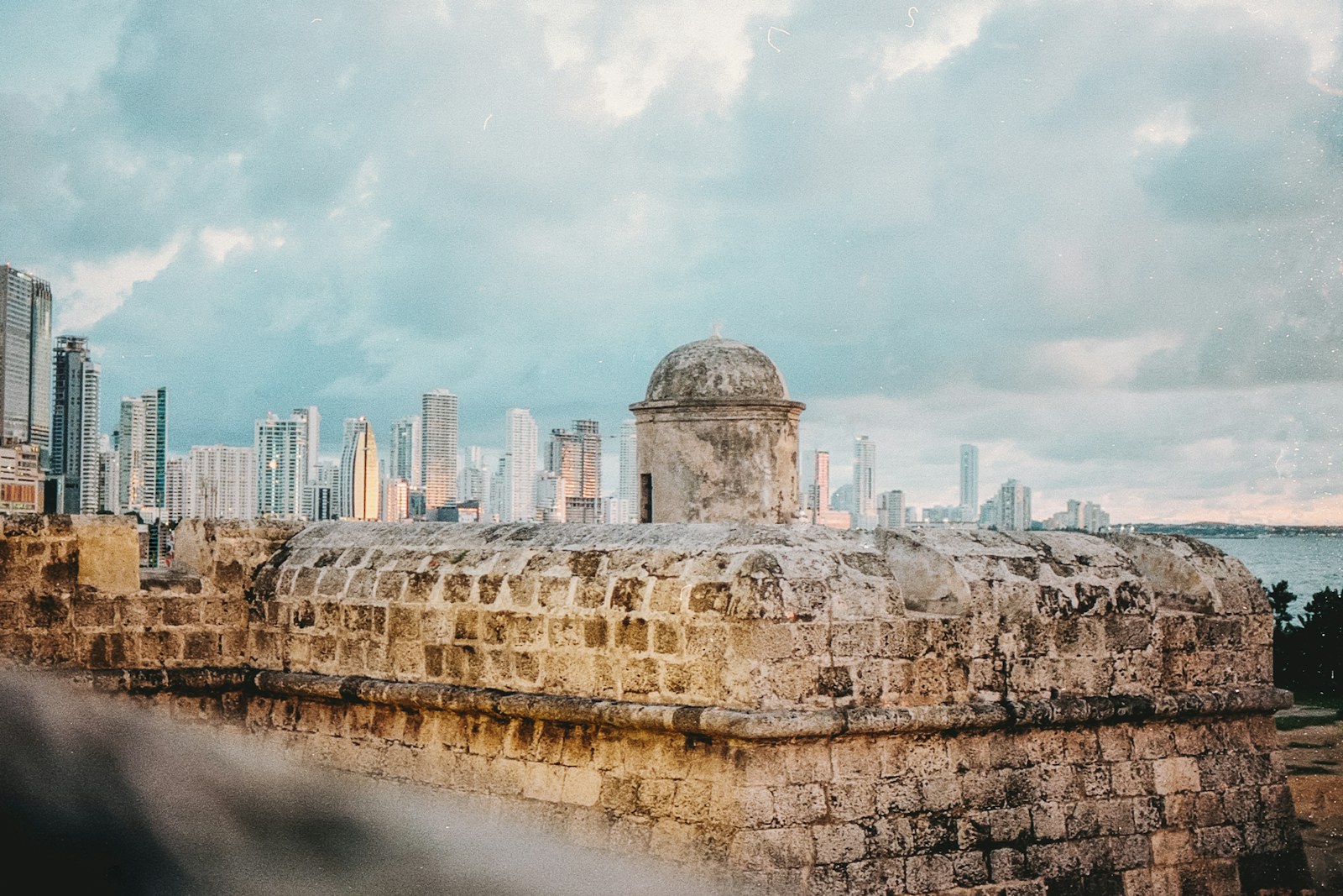 Watchtower of the Cartagena city walls, framed against the Bocagrande skyline at sunset
