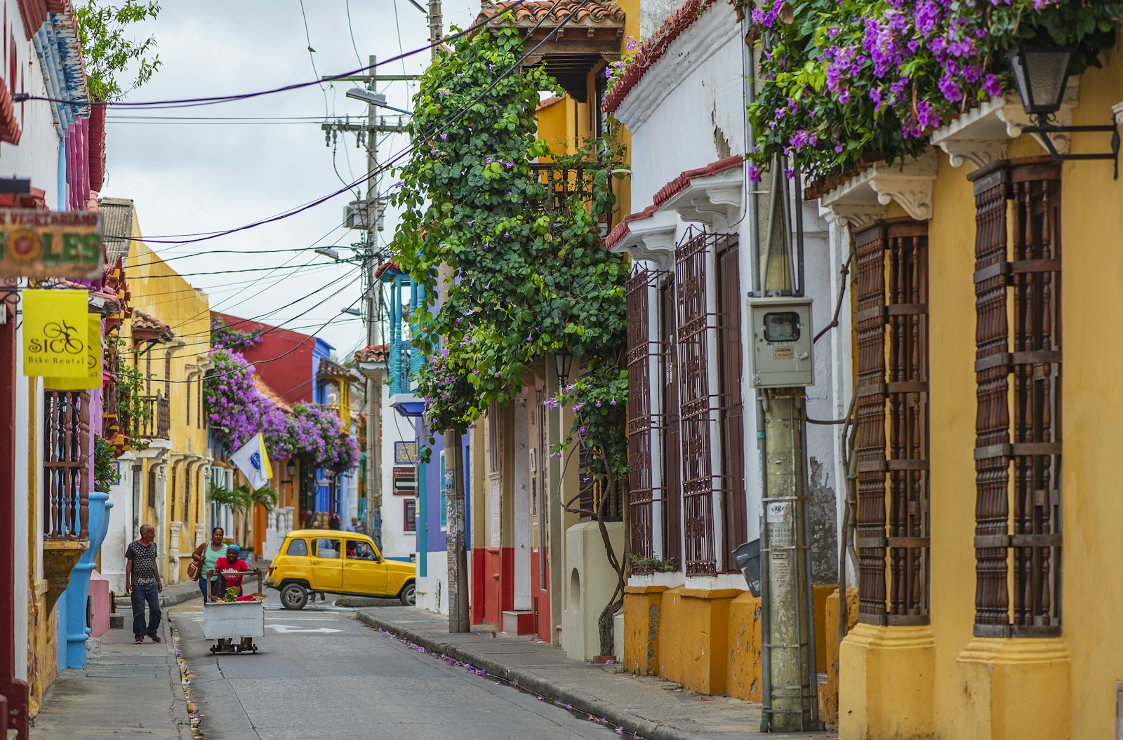 A colorful colonial street in Getsemaní, Cartagena, with bougainvillea and a yellow vintage car