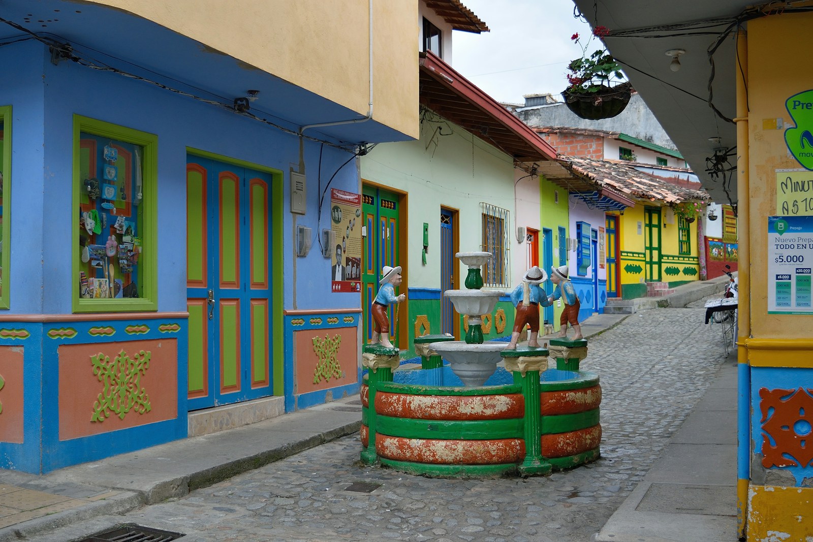 The painted zócalos and colorful houses of Guatapé village, with a small fountain and cobblestone street